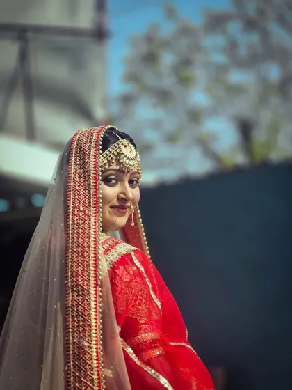 A classic over-the-shoulder bridal pose. This shot beautifully captures the details of the embroidered veil, the side profile, and the delicate smile of the model.