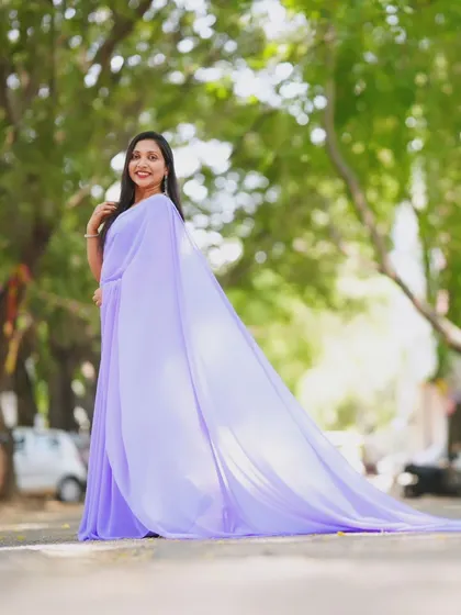 A wide shot showing the full, dramatic effect of the lavender trail saree in an outdoor setting.