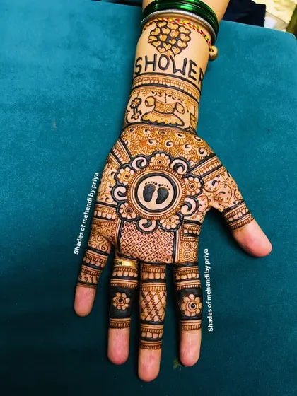 A classic baby shower design with tiny footprints at the center of a mandala. The wristband has the word 'Shower' and a drawing of a cradle.