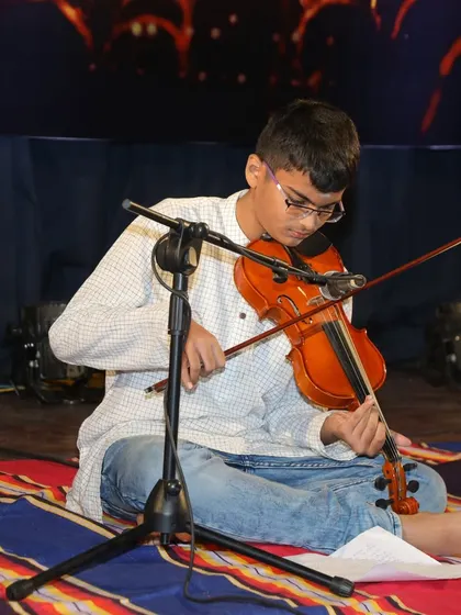 A close-up of Amogh's focused expression and skillful playing during his violin recital at Kalaa Sangama.