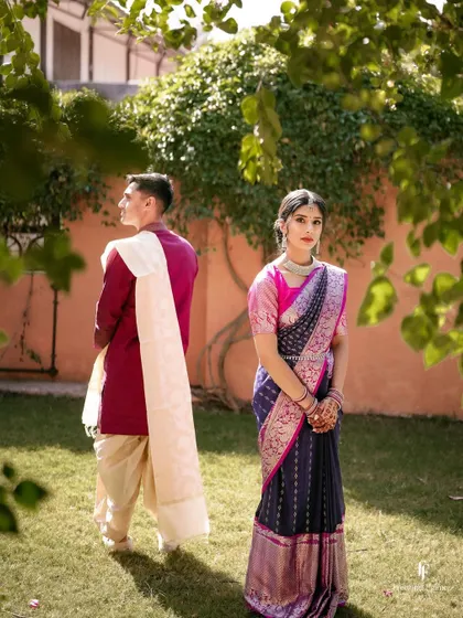 A creative portrait of the couple in a garden, with the groom facing away and the bride looking towards the camera, creating a sense of story and intrigue.