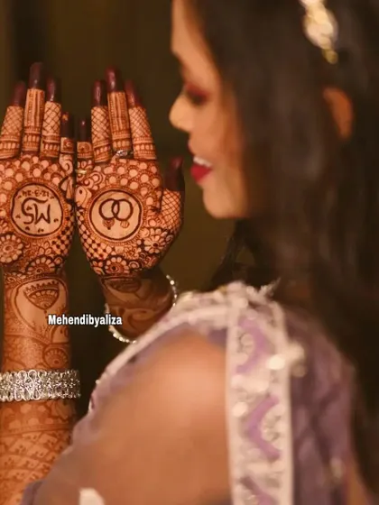 A beautiful glimpse of an engagement bride showing off her henna, which features the couple's initials and intertwined rings.