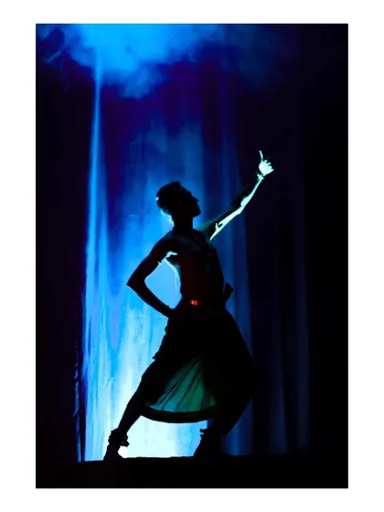 A dramatic silhouette of my pose from "Tyāgarāja Hṛt Sādana." The stark lighting against the blue background creates a powerful and memorable image.