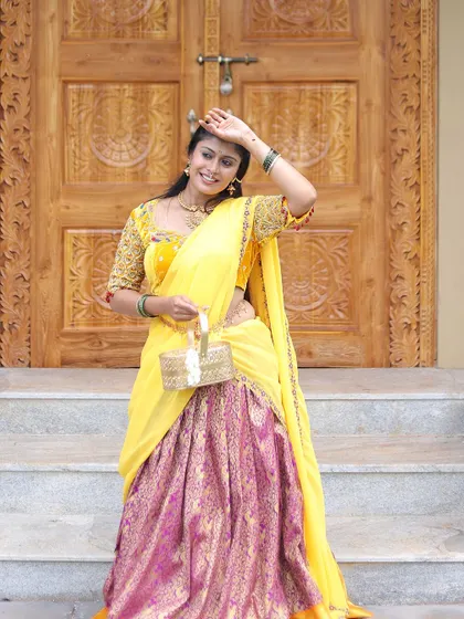 A close-up of a yellow and pink brocade half saree, showcasing the rich fabric and traditional design.