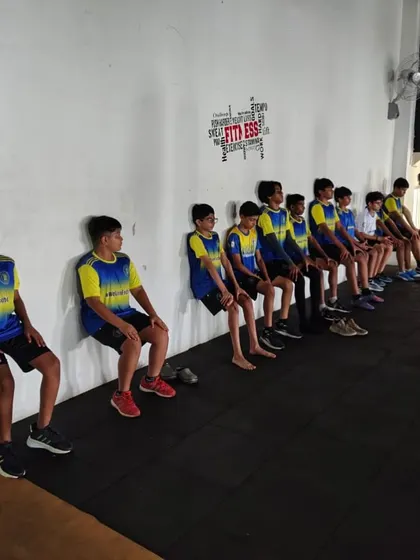 Players perform wall-sits during a strength and conditioning session in the on-campus fitness center. This highlights our focus on building the physical strength and endurance essential for a modern footballer.