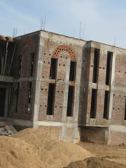 A wide-angle shot of a residential project during the construction phase. The image captures the building's skeleton, revealing the grid of columns and beams that form its structural core.
