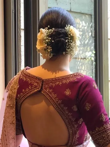 A clear back view of a braided bun with fresh flowers. This updo is a beautiful option for brides who want a touch of tradition with a romantic flair.