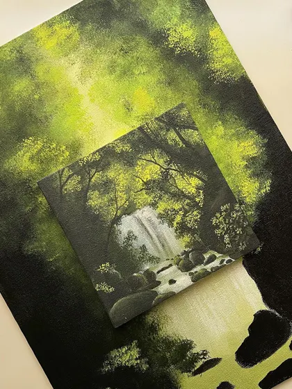 A photo showing my small, finished waterfall painting placed on top of the larger, unfinished version. Seeing the small one complete motivated me to finish the big one.