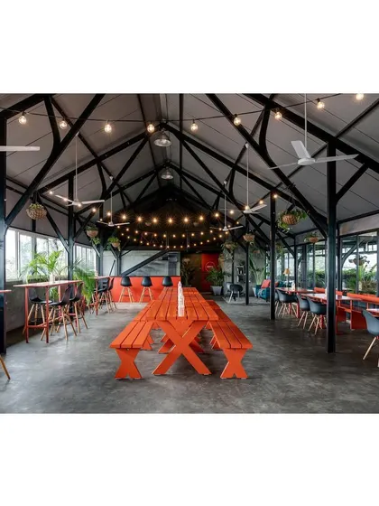 The full view of the rooftop venue shows its open, barn-like structure with a high vaulted ceiling. This design maximizes the sense of space and allows for large-scale events, while hanging plants and string lights maintain a warm, inviting atmosphere.