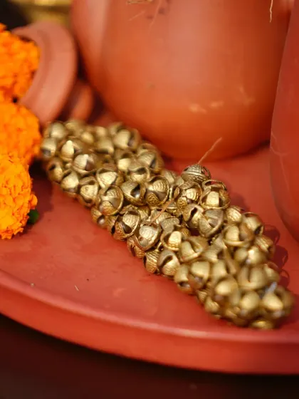 A close-up of traditional ghungroos (ankle bells) placed on a terracotta tray, a small but significant cultural detail.