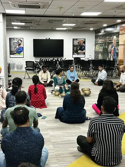 A wider view of a corporate group session where employees are seated in a circle. This format fosters a sense of community and shared experience, enhancing the overall benefits of the practice.