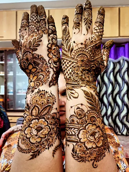 A client proudly displays her full-hand bridal henna, featuring large floral elements.