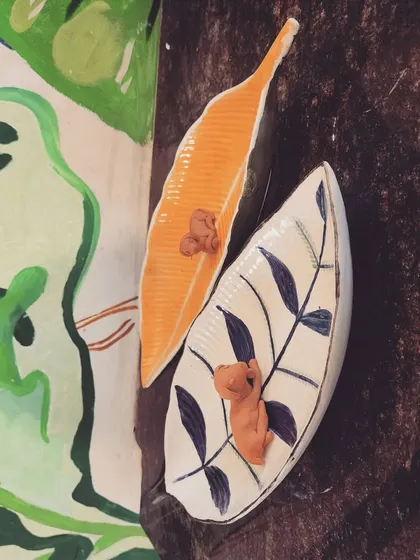 These leaf shaped ceramic trays, one unpainted and one with a simple, elegant design, are perfect for holding trinkets or as decorative pieces.
