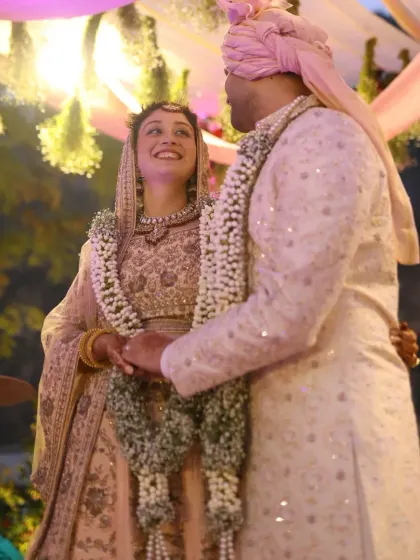 The couple exchanges garlands during their Varmala ceremony, smiling at each other under the soft evening lights at their Taj Corbett wedding.