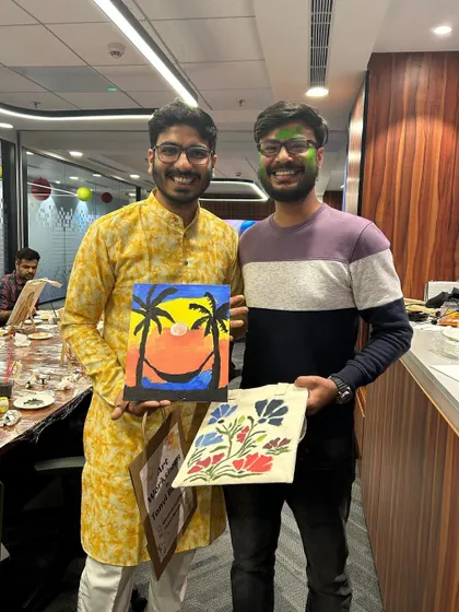 Two participants from the Houlihan Lokey workshop with their finished pieces. One beautiful sunset canvas and one stunning floral tote bag.