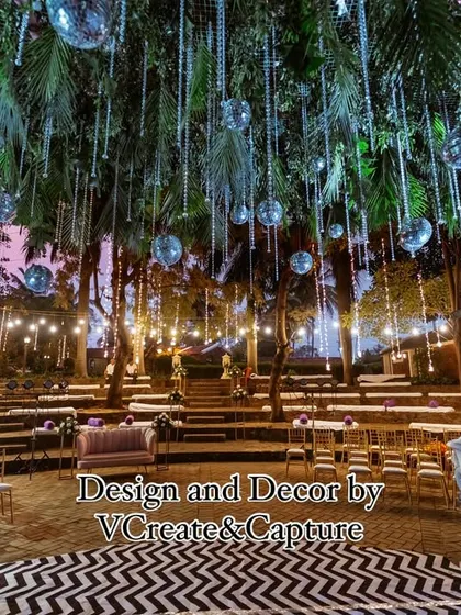 The sangeet stage is set under a ceiling of hanging greenery and disco balls, with a modern black-and-white chevron dance floor ready for the party.