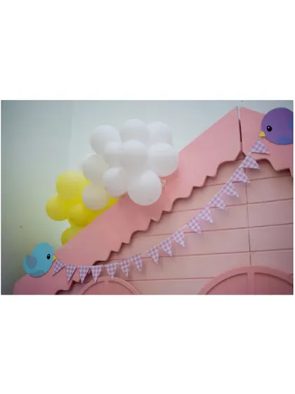 A close-up of the pink birdhouse roofline, adorned with a mini pennant banner and cute bird cutouts.