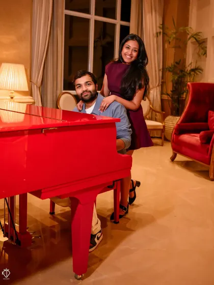 A fun and elegant shot indoors with a vibrant red piano, showing that romantic moments can be created anywhere, not just outdoors.