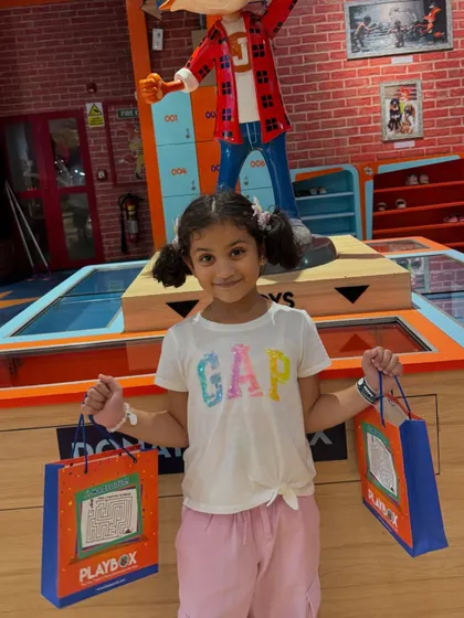 A happy girl posing with her goody bags after a fun-filled Sunday at our play area.