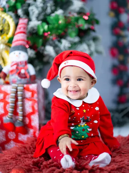 Little Ms. Claus is ready for Christmas. The festive red outfit and snowman prop create a classic holiday portrait.