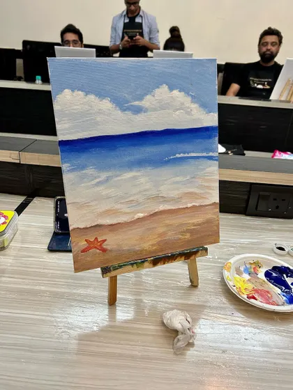 A finished beach painting on an easel, ready to be taken home. A beautiful memory of a creative day.