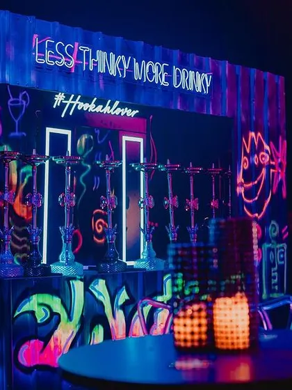 A custom-built hookah bar with glowing graffiti art. The neon signs and fun slogans created a vibrant and social corner for guests to enjoy.