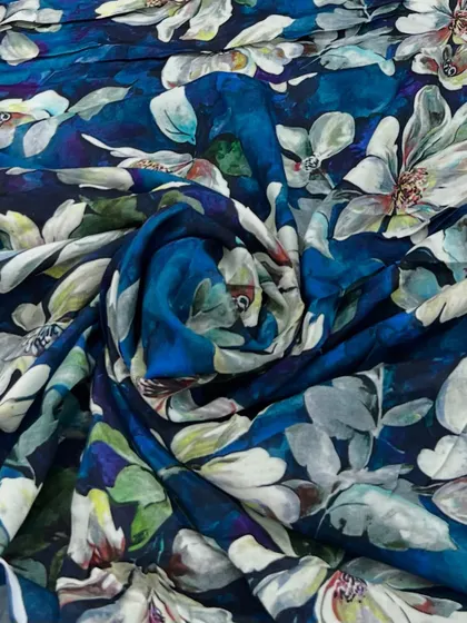 A stunning printed muslin fabric with a watercolor floral design on a deep blue base, perfect for creating artistic and flowing outfits.
