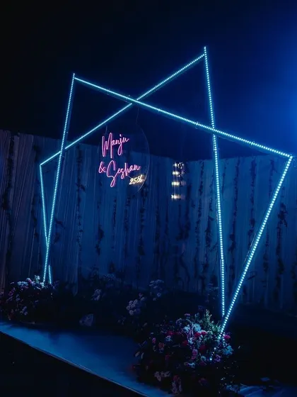 A personalized party backdrop with a geometric LED frame and a custom neon sign with the couple's names. It's a great way to make any celebration feel unique.