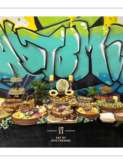 An edgy and modern grazing table set against a graffiti wall, showing our ability to adapt our style to any venue or theme.