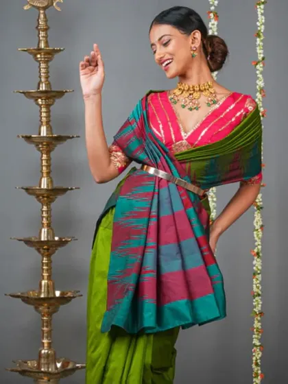 A fun and festive look, the model wears a bright pink blouse and a colorful saree, accessorized with a statement necklace.