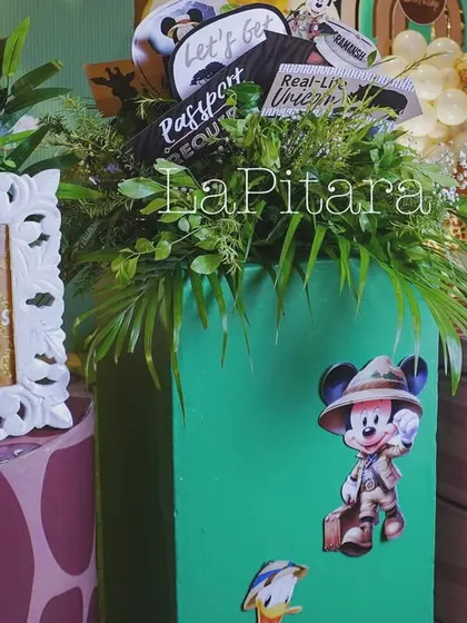 A close-up of the decor, showing personalized photo frames and lush greenery on top of themed pedestals.