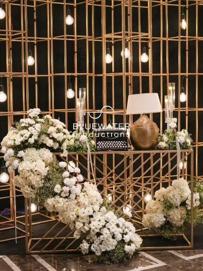 A photo-op corner with a golden grid backdrop, vintage typewriter, and cascading white florals.
