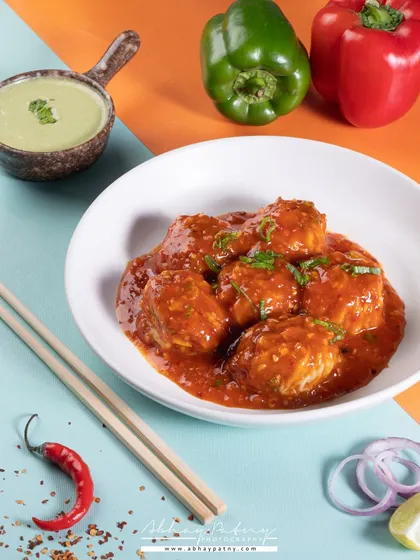 The use of a split-color background adds a playful and modern touch to this shot of Manchurian. It's a great way to make a classic dish stand out on a delivery app or social media.
