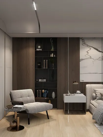 This bedroom corner features a comfortable reading chair and a dark wood-paneled wall with integrated shelving for books and decor.