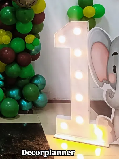 The marquee '1' light adds a bright and celebratory touch to the jungle setup, perfectly highlighting the milestone of a first birthday.
