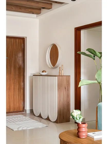 The foyer's concealed shoe cabinet in 'The Boho Escape' features unique inverted arch paneling. It serves as a beautiful console table, proving that functional pieces can also be design statements.