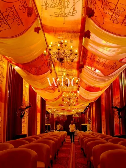 Divine decor for a divine occasion. The entrance to a Mata Ki Chowki, with a grand walkway draped in fabrics printed with holy scriptures and lit by chandeliers.