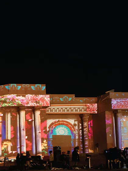 The monumental stage facade being transformed by colorful projection mapping. This technology allowed us to paint the ancient Roman-inspired architecture with light, creating a dynamic and ever-changing visual experience.