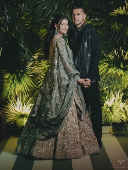A stunning couple portrait from a Sangeet night in Udaipur. The bride's emerald and gold lehenga perfectly complemented the lush green backdrop.