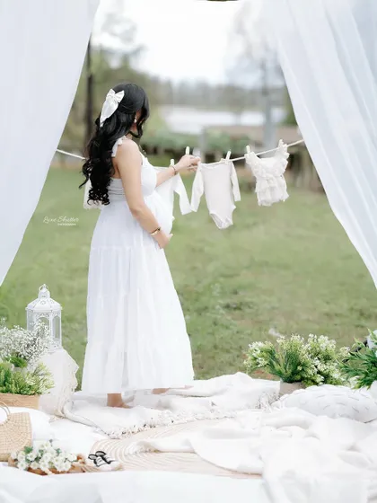 A dreamy outdoor scene. The flowing white curtains and the line of baby clothes create a soft, ethereal frame for this beautiful portrait.