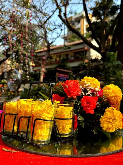 A simple yet creative centerpiece for a Mehendi, using a mirrored plate and a cutting chai glass holder filled with marigold petals.
