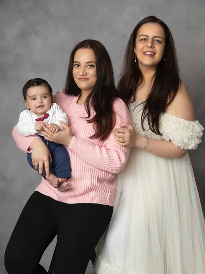 A portrait of two sisters with the family's new baby. This photo celebrates sisterhood and the joy of welcoming a new member to the family.