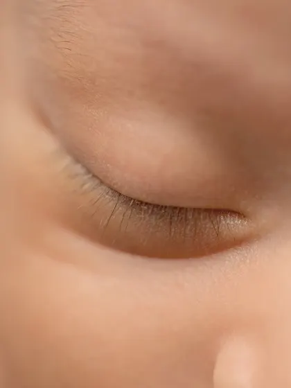 A macro shot of a newborn's delicate eyelashes, showcasing the incredible detail we capture in our sessions.