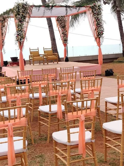 A simple yet elegant mandap setup for a beach wedding. The focus here is on the clean lines and the beautiful view, with peach drapes and white floral accents adding a touch of softness.
