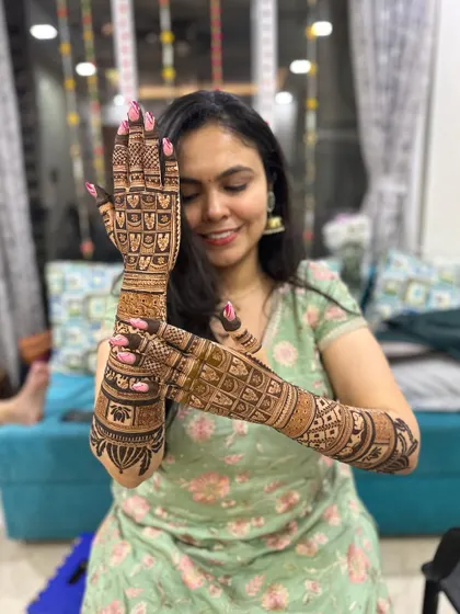 A happy bride showing off the intricate jaal work on the back of her hands.