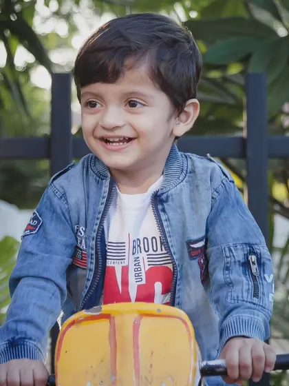 Play is a child's natural form of expression. This happy moment on a ride-on toy shows the simple joys of being a kid, captured with a candid approach.