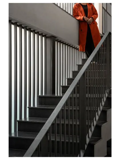 The interior staircase is designed with simple, strong lines using steel and concrete. The vertical balusters echo the fins on the exterior, creating a cohesive design language throughout the structure.