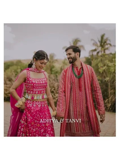 A candid shot of the couple walking hand-in-hand at their Haldi ceremony. Their vibrant pink outfits and happy expressions perfectly capture the festive mood.