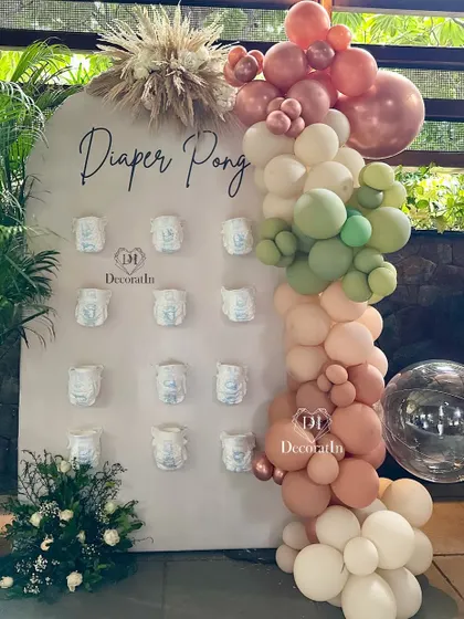 A closer view of the "Diaper Pong" board, framed by a beautiful balloon garland.