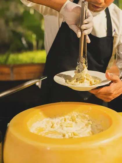 A chef serves a plate of fresh pasta from our signature cheese wheel station.